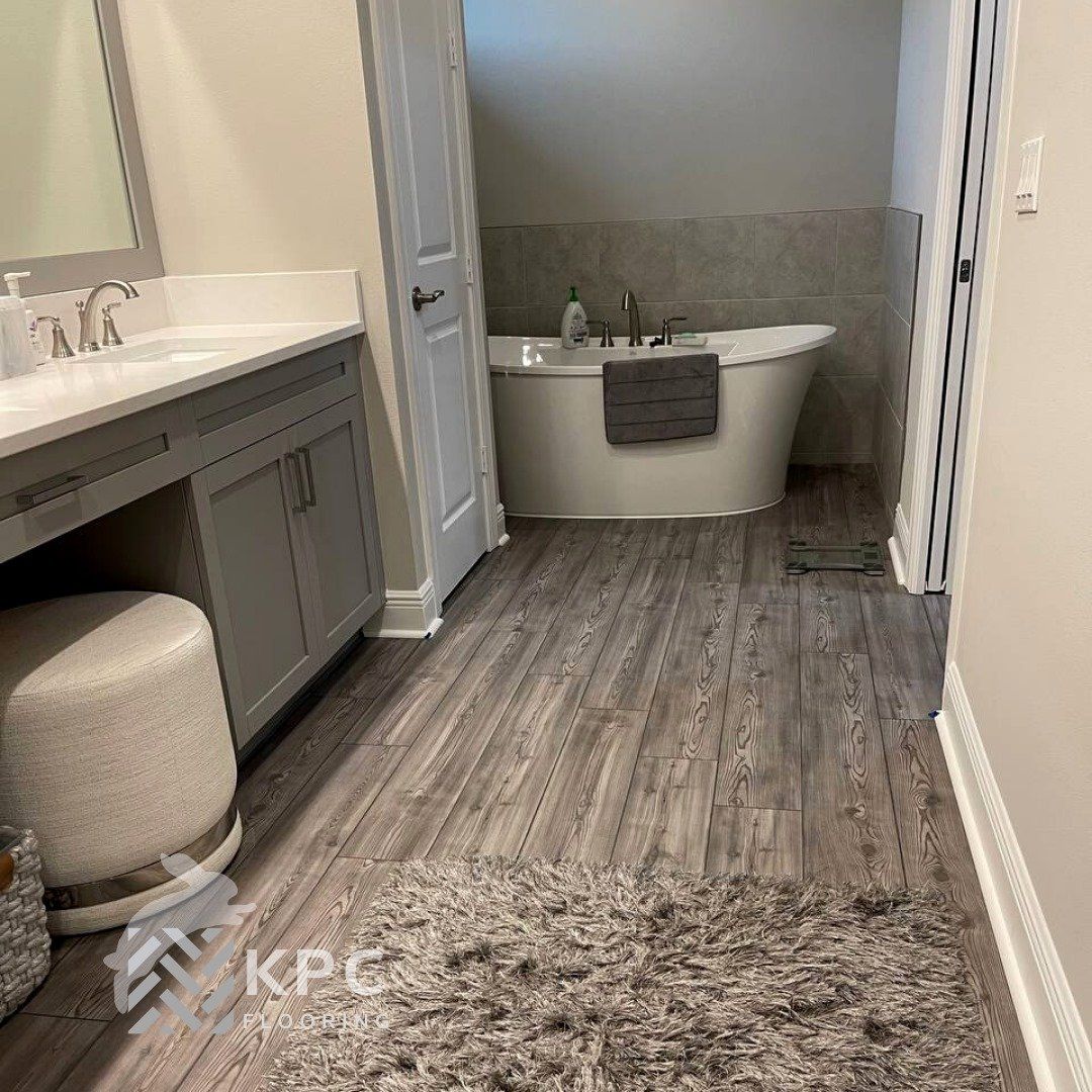 Gray wood-look plank flooring around a freestanding tub in a bathroom