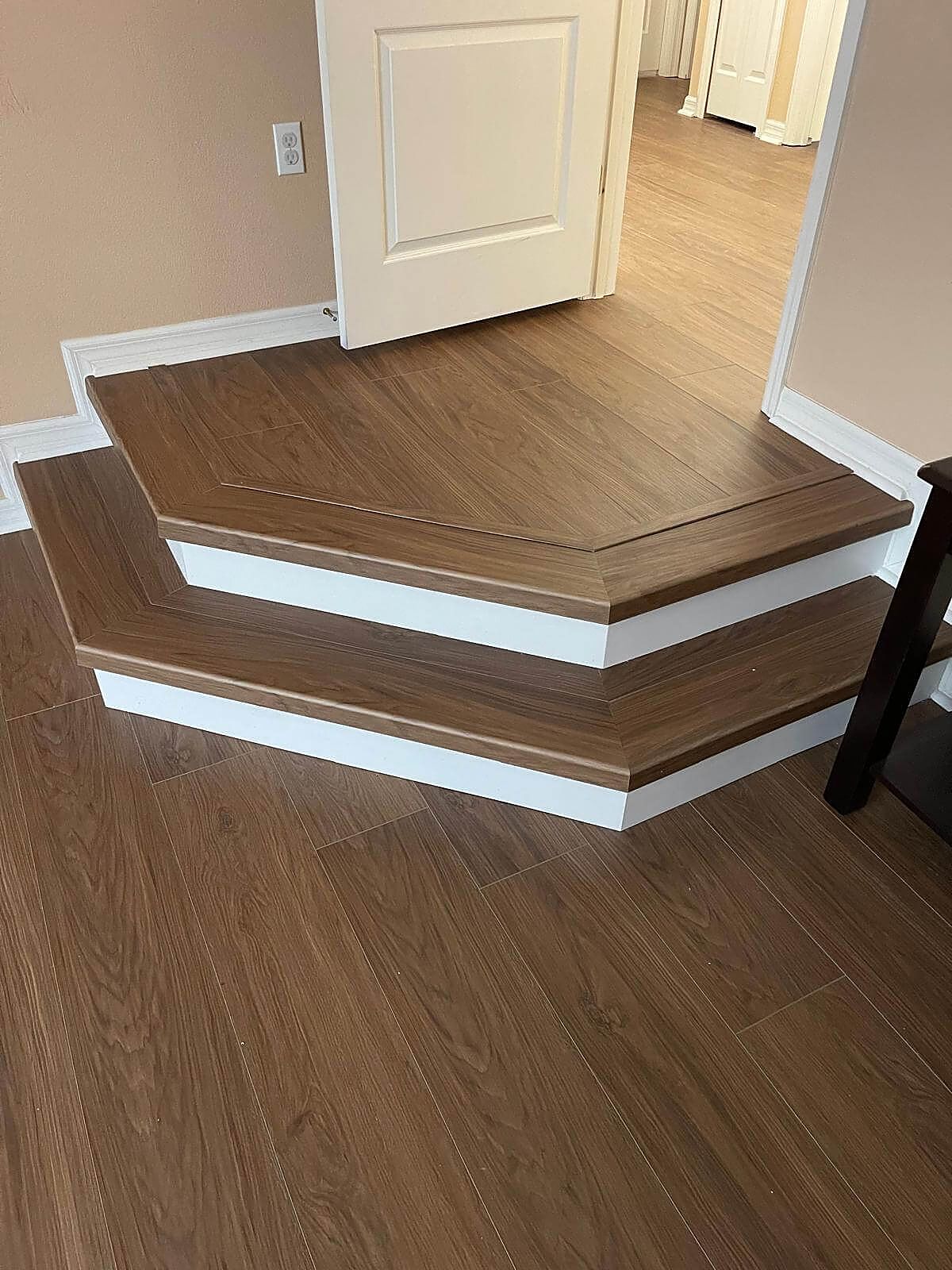 Two angled steps with wood-look plank treads, white risers and matching floor
