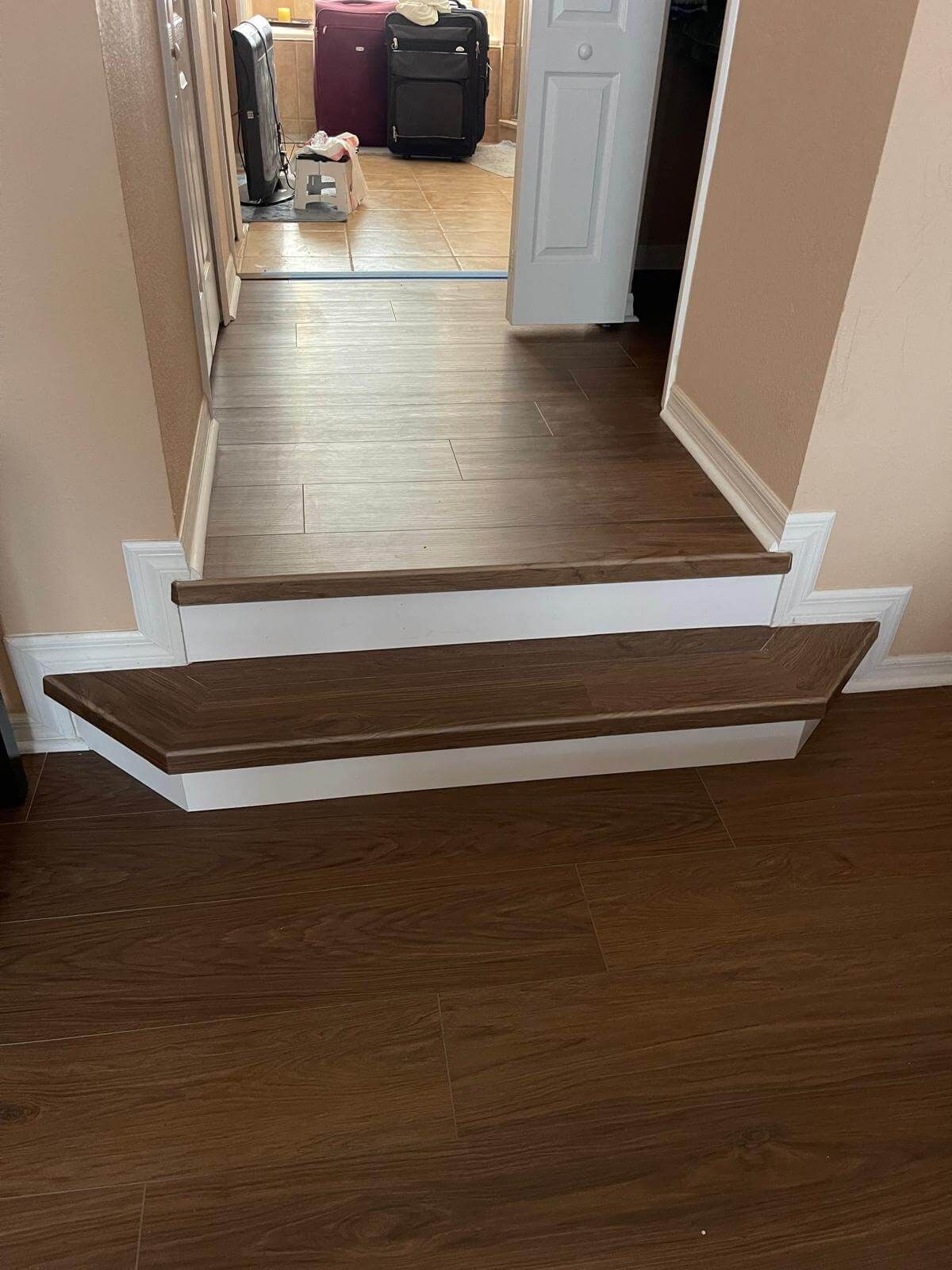 Wood-look vinyl plank step-up into a hallway with matching flooring