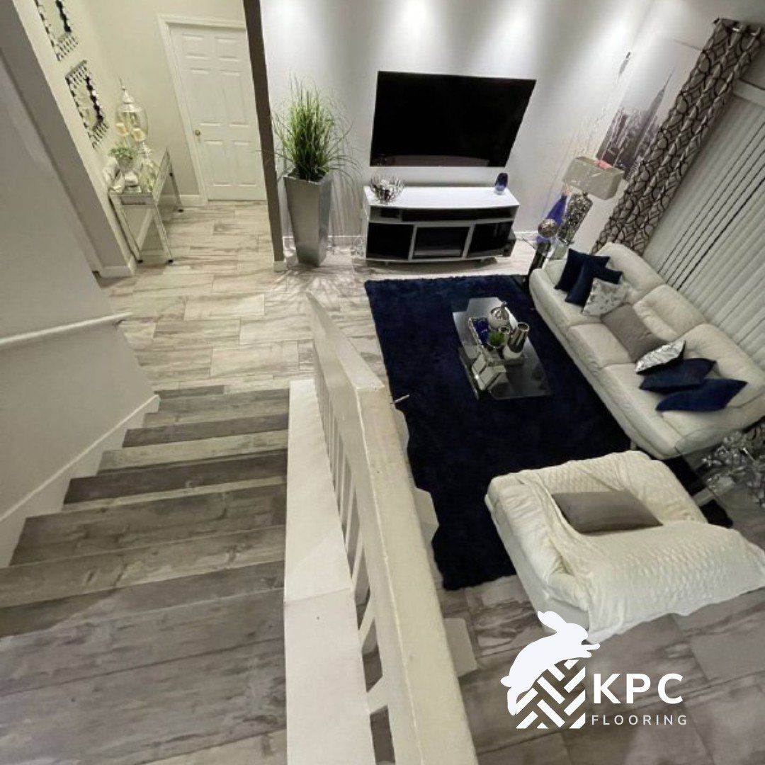 Gray wood-look plank flooring on a staircase that goes down to a living room
