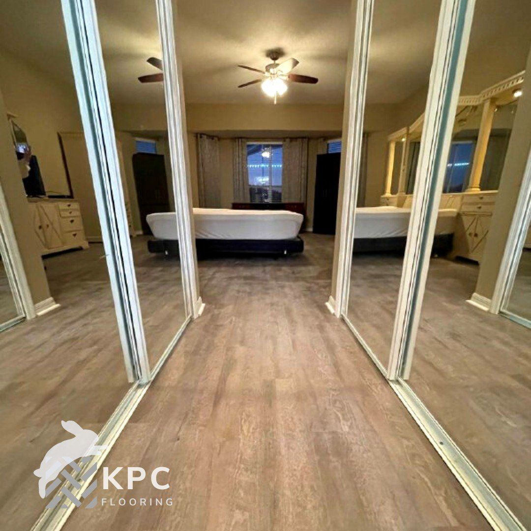 Wood-look vinyl plank floor running into a bedroom framed by mirrored closet doors
